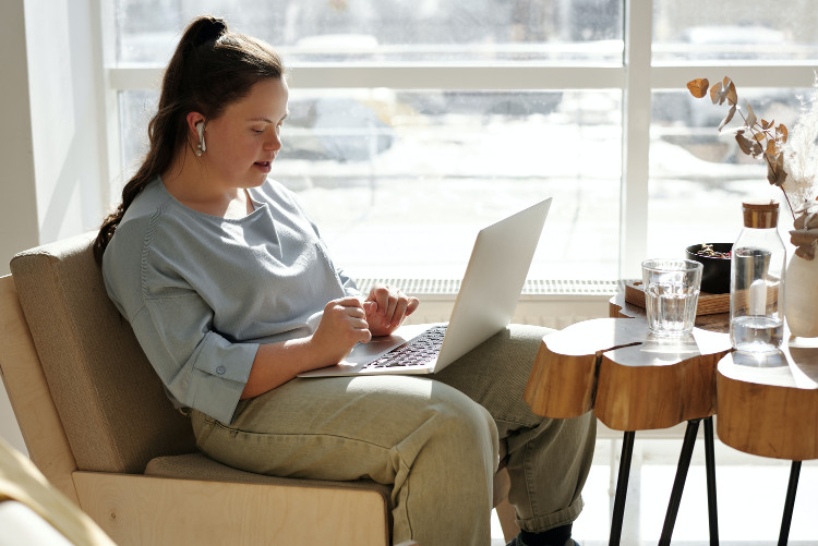 girl with disability sitting on a couch using a laptop 