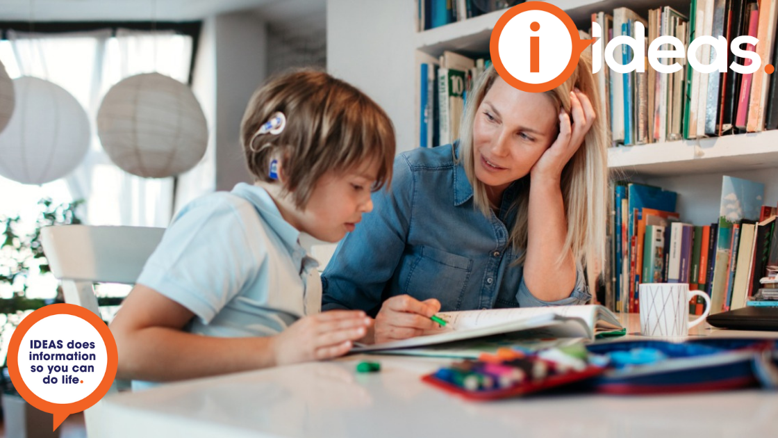 Child with cochlear implant sitting alongside an adult, learning