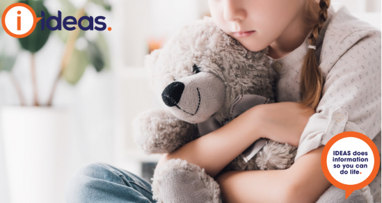 A young girl with a plait in her hair and a thoughtful look on her face is hugging a teddy bear. The teddy is smiling.