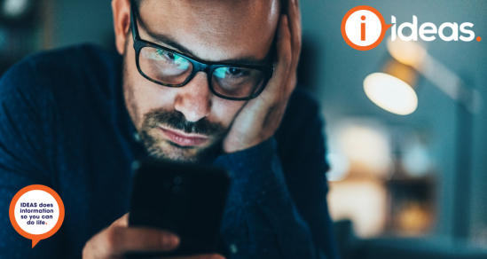 Man with glasses, resting hand on forehead, looking at his phone.