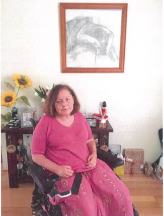 A dark-haired lady in a wheelchair wearing a bright pink dress